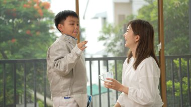 Eskrim kıyafeti giymiş bir çocuk anneleriyle birlikte yaklaşan müsabaka gününe hazırlanmak için eskrim antrenmanından önce süt ve spor malzemeleri hazırlıyor.