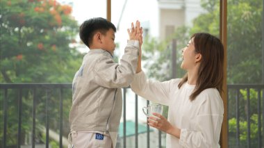 Eskrim kıyafeti giymiş bir çocuk anneleriyle birlikte yaklaşan müsabaka gününe hazırlanmak için eskrim antrenmanından önce süt ve spor malzemeleri hazırlıyor.