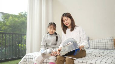 Eskrim kıyafeti giymiş bir kız, yaklaşan müsabaka gününe hazırlanmak için eskrim antrenmanından önce annesiyle spor malzemeleri hazırlıyor.