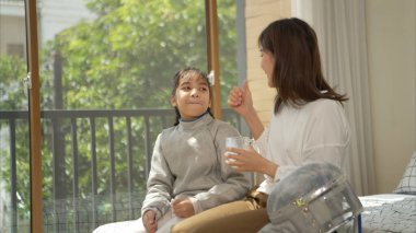 Eskrim kıyafeti giymiş bir kız, yaklaşan müsabaka gününe hazırlanmak için eskrim antrenmanından önce annesiyle spor malzemeleri hazırlıyor.
