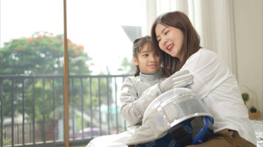 Eskrim kıyafeti giymiş bir kız, anneleriyle birlikte yaklaşan müsabaka gününe hazırlanmak için eskrim antrenmanından önce süt ve spor malzemeleri hazırlıyor.