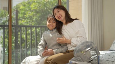 Eskrim kıyafeti giymiş bir kız, anneleriyle birlikte yaklaşan müsabaka gününe hazırlanmak için eskrim antrenmanından önce süt ve spor malzemeleri hazırlıyor.