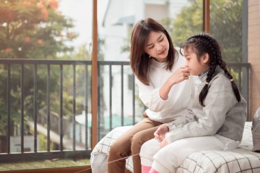 Eskrim kıyafeti giymiş bir kız, anneleriyle birlikte yaklaşan yarışma gününe hazırlık için eskrim antrenmanından önce yiyecek ve spor malzemeleri hazırlıyor.