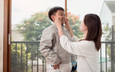 Eskrim kıyafeti giymiş bir çocuk anneleriyle birlikte yaklaşan müsabaka gününe hazırlanmak için eskrim antrenmanından önce yiyecek ve spor malzemeleri hazırlıyor.
