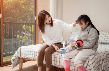 Eskrim kıyafeti giymiş bir kız, anneleriyle birlikte yaklaşan yarışma gününe hazırlık için eskrim antrenmanından önce yiyecek ve spor malzemeleri hazırlıyor.