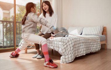 Eskrim kıyafeti giymiş bir kız, anneleriyle birlikte yaklaşan yarışma gününe hazırlık için eskrim antrenmanından önce yiyecek ve spor malzemeleri hazırlıyor.