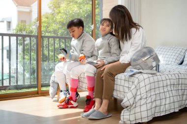 Bir kız ve oğlan, anneleriyle eskrim kıyafetleri içinde yaklaşan müsabakaya hazırlanmak için eskrim antrenmanından önce yiyecek ve spor malzemeleri hazırlıyorlar.