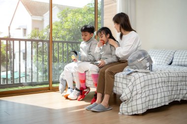 Bir kız ve oğlan, anneleriyle eskrim kıyafetleri içinde yaklaşan müsabakaya hazırlanmak için eskrim antrenmanından önce yiyecek ve spor malzemeleri hazırlıyorlar.