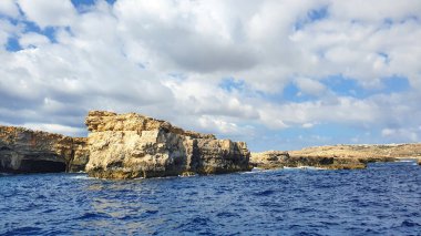 Incredibly beautiful and fabulous rocky coastline near Malta in the Mediterranean Sea against the backdrop of romantic white clouds and enchanting sea.