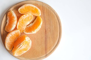 Olgun, sulu, lezzetli portakal dilimleri yuvarlak bir mutfak tahtasında yatıyor..