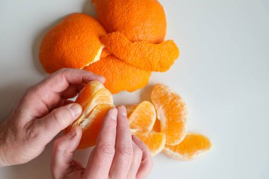 Erkeklerin elleri olgun, sulu bir portakalı soyar ve birkaç dilime böler..