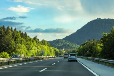 Gün batımında, Avrupa Alpleri 'ndeki tepelerde çok sayıda ağaçla koşan bir otoyol manzarası..