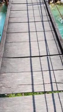 Slovenya 'nın turkuaz dağ nehri üzerinde kayalar ve ormanlarla çevrili ahşap bir asma köprü. Seyahat, doğa ve macera temaları için mükemmel.