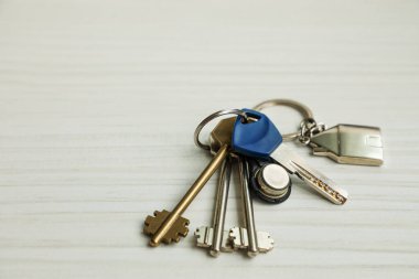 Hafif ahşap bir masaya yerleştirilmiş parlak metal anahtarlar. Güvenliği, mülkiyete erişimi ve gayrimenkul mülkiyetini sembolize ediyor..