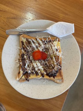 Çikolata soslu tost ve beyaz tabakta çilek.