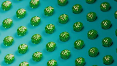 Pürüzsüz bir turkuaz yüzeye yerleştirilmiş şeffaf yeşil üç boyutlu beyin modelinin yakın plan görüntüsü, merkezi beyne keskin odaklı sığ alan derinliği, parlak yansıtıcı doku, stüdyo aydınlatması, soyut nörobilim konsepti, canlı renkler, tıbbi