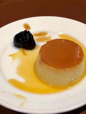 Tatlı, yoğunlaştırılmış sütlü puding, erik ve karamel soslu tabak.