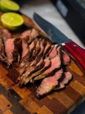 Et, yanında bıçak ve arka planda limon olan bir kesme tahtasının şeritlerine ayrılmış.