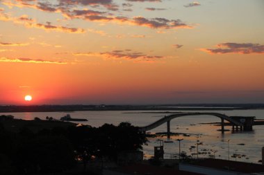Brezilya, Mato Grosso do Sul, Corumb 'daki Paraguay Nehri üzerinde çarpıcı bir günbatımı gökyüzünü aydınlatır. Ateşli turuncu ve altın renkler suya çok güzel yansıyor. Huzurlu ve hayranlık verici bir sahne yaratıyor..