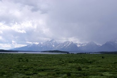 Fırtına bulutları Teton Sıradağları üzerinde toplanıyor ve Jackson Gölü ön planda, Grand Teton Ulusal Parkı, Wyoming.