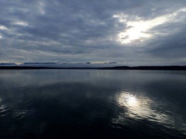 Buzul Körfezi Ulusal Parkı 'nda sakin bir akşam. Güneşin yansıması bulutların arasından sakin sulara doğru kırılıyor..