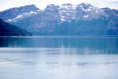 Sakin sular, Buzul Körfezi Ulusal Parkı 'ndaki engebeli dağları yansıtıyor. Alaska' nın dingin ve el değmemiş doğal güzelliğini sergiliyor..
