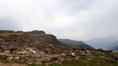 Uçsuz bucaksız Rocky Dağları 'ndan geçen yüksek irtifalı bir yol bulutlu bir gökyüzü altında, seyahat ve macera temaları için mükemmel..