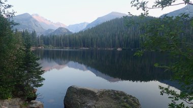 Kayalık kıyılar ve yemyeşil ağaçlarla çerçevelenmiş sakin bir dağ gölü. Yumuşak alacakaranlık parıltısının altındaki sakin sularında yansıyan orman tepeleri..