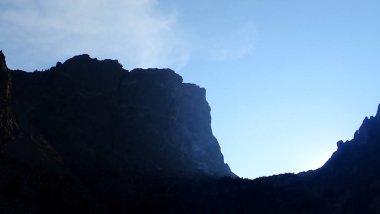 Görkemli dağ uçurumu parlayan bir gökyüzüne karşı, Rocky Dağı Ulusal Parkı 'ndaki doğanın zıtlıklarının huzurlu güzelliğini yakalıyor.