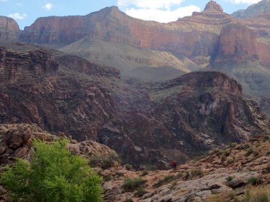 Kırmızı bir ceket giyen yalnız bir yürüyüşçü, Parlak Melek Yolu boyunca Büyük Kanyon 'un engebeli manzarasının derinliklerine doğru ilerler. Uçsuz bucaksız kaya oluşumları bir zaman hikâyesi anlatırken, ön plandaki yeşil yapraklar kuraklığa zıt düşüyor.