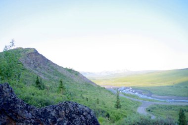 Dolambaçlı nehir ve manzaralı yol yemyeşil bir vadi boyunca engebeli tepeler ve uzak dağlarla Denali Ulusal Parkı, Alaska