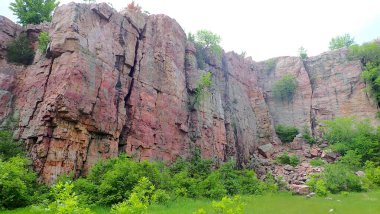 Minnesota 'daki Blue Mound State Parkı' nda kayalık bir enkaz alanının ve yemyeşil çimenliğin üzerinde kırmızı kuvart kulelerden oluşan dramatik bir duvar..