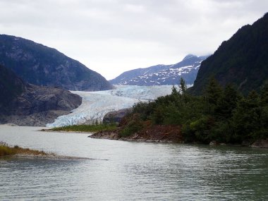 Mendenhall Buzulu 'ndan gelen buz, Juneau Alaska' daki kayalık kayalıklar ve yemyeşil ormanlarla çevrili göle akar.