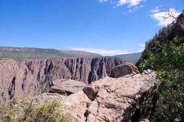 Sert kaya oluşumları ve açık mavi gökyüzü ile Gunnison 'un Kara Kanyonu' nun dramatik uçurum manzarası
