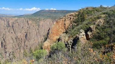 Gunnison Ulusal Parkı 'nın Kara Kanyon' unda kayalık katmanlı kaya oluşumları olan kayalık ve fırça gibi bir arazi.