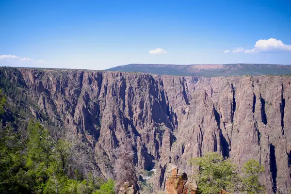Güneşli bir günde Gunnison Kanyonu 'nun sarp kayalıkları ve Gunnison Nehri' nin aşağısındaki Kara Kanyon manzarasını süpürüyor