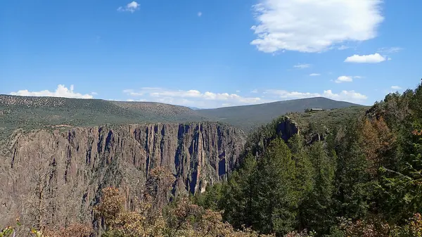 Kara Kanyon 'un dramatik uçurumları ve mavi gökyüzünün altındaki yeşil ormanlarla panoramik görüntüsü.