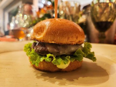 Lezzetli gurme mini burger. Görüntü, sofistike bir ortamda etin ve taze malzemelerin lezzetini yakalar. Yemek pişirme ve gastronomik deneyimlere olan tutkusunu yansıtır..