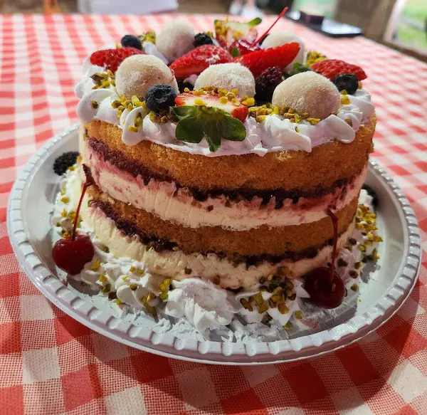 Çekici ve renkli bir doğum günü pastası, krema katmanları, taze çilek, böğürtlen ve şam fıstığı ile süslenmiş..