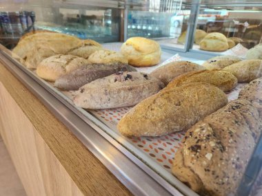 Bir vitrinde gösterilen karşı konulamaz bir ekmekler seçimi çıtır çıtır dokularını ve çeşitli renklerini gözler önüne seriyor..