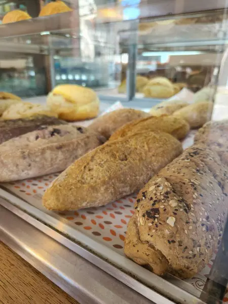 Bir fırın vitrininde sergilenen çeşitli taze ekmekler zengin bir dokuyu ve altın kabuğu vurguluyor..