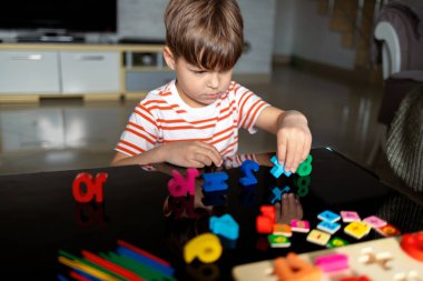 Bir çocuk ahşap sayılar ve sopalarla matematik problemi yaratır ve çözer. Ev ortamında oynayarak bağımsız öğrenme. Kavramları: sayma, matematik düşünme, bağımsız öğrenme, eğitim oyunu