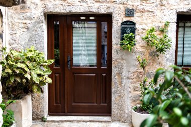 Karadağ 'ın Budva Eski Kentinde Konforlu Avlu Tasarım ve Ev Girişi, modern bir kapı, geleneksel taş duvar ve canlı saksı bitkilerini harmanlıyor.