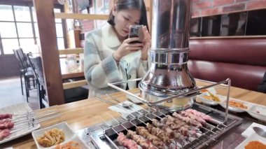 Koreli kız Kore 'deki Çin restoranında telefonuyla Çin şiş resimleri çekiyor. Yüksek kalite 4k görüntü