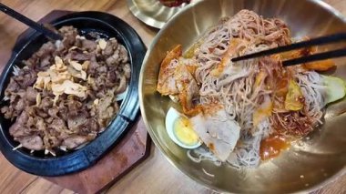 Kore usulü soğuk erişte, naengmyeon. Dilimlenmiş salatalık, turp turşusu. Lezzetli yemekler. Yüksek kalite 4k görüntü