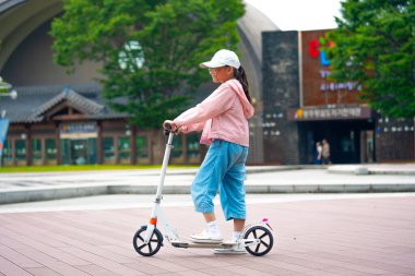  Asyalı kız scooter 'a binecek. Uzayı kopyala Yüksek kalite fotoğraf