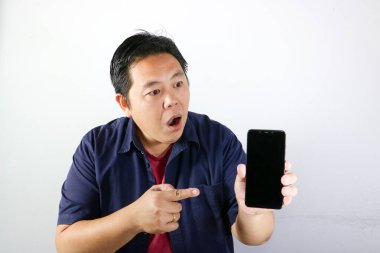 Şaşırmış, şaşırmış ve yakışıklı adamın akıllı telefonunu izole edilmiş beyaz arka planda kullanışının çarpıcı ifadesi..