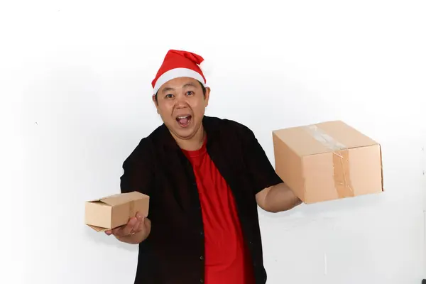 Noel Baba şapkası takan bir adam iki hediye kutusu tutar: Mutlu, mutlu, neşeli, arkadaş canlısı, mutluluk, pozitif, neşeli, kendine güvenen, çekici, havalı, mutlu adam, keyif al, heyecanlı., 