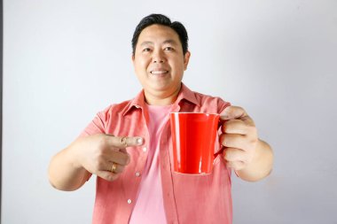 Kırmızı bardağı tutan ve kırmızı bardağı işaret eden adam.