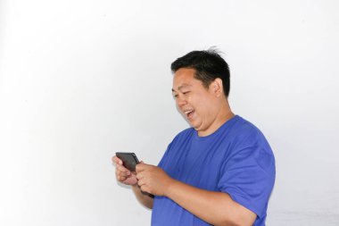 Mavi tişörtlü adam heyecanlı bir şekilde mobil oyun oynuyor.